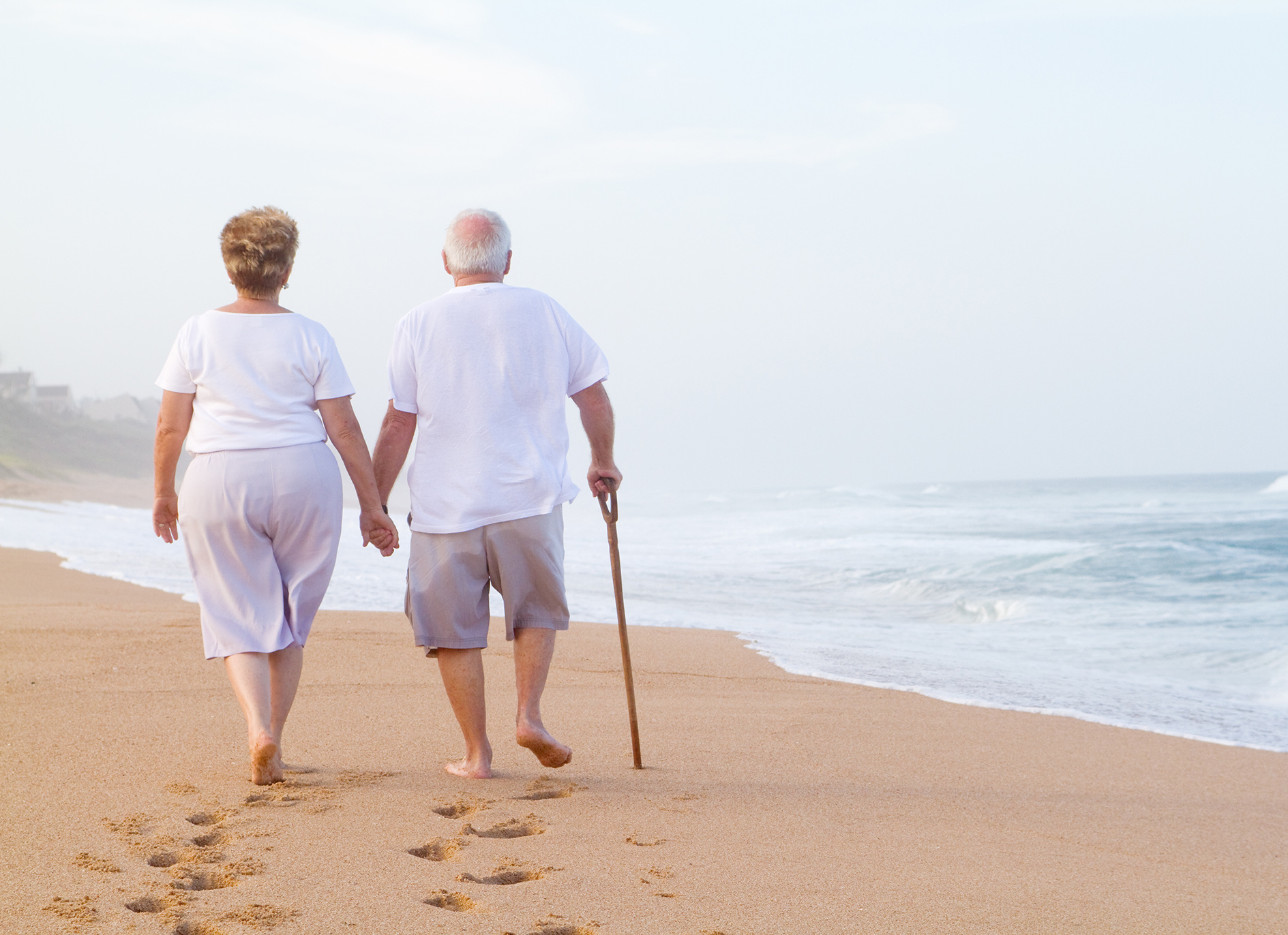 senior couple holding hands on beach