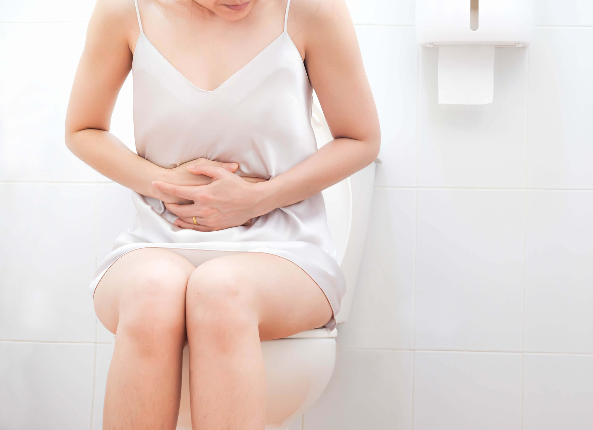 women wearing white nightwear on toilet holding stomach